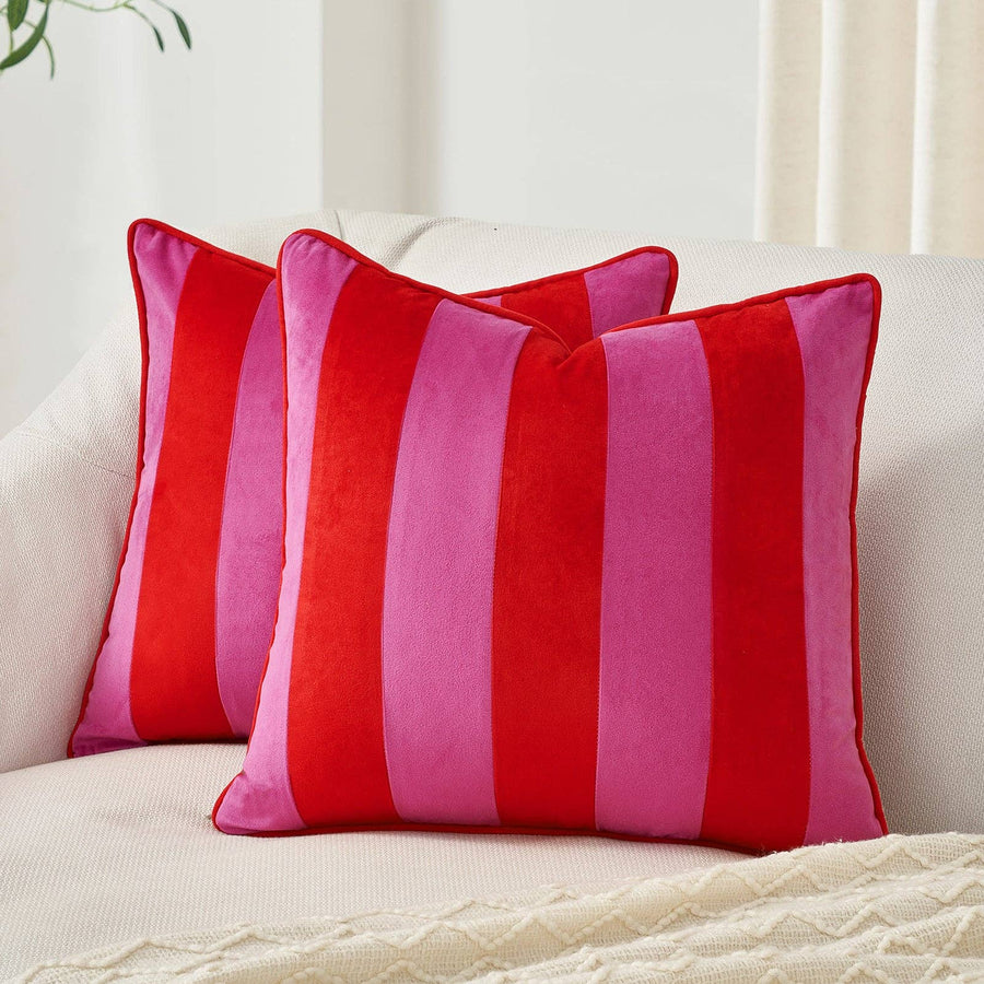 Two red and pink striped pillows on a white sofa.