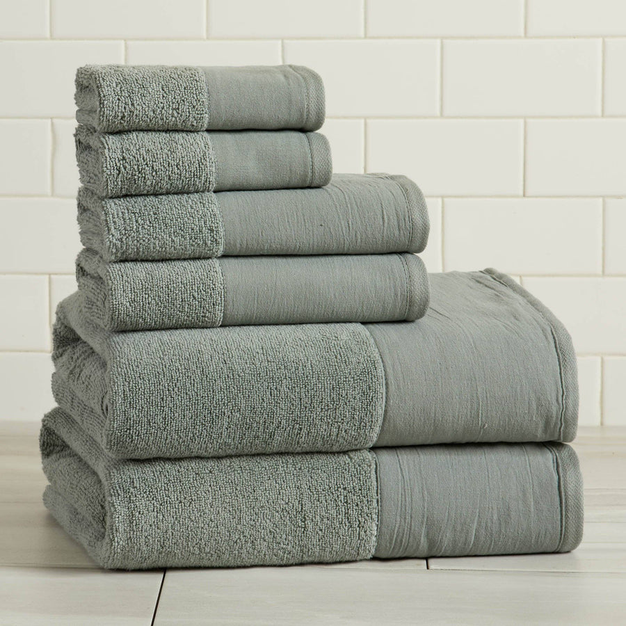 Stack of gray towels on a white tiled floor